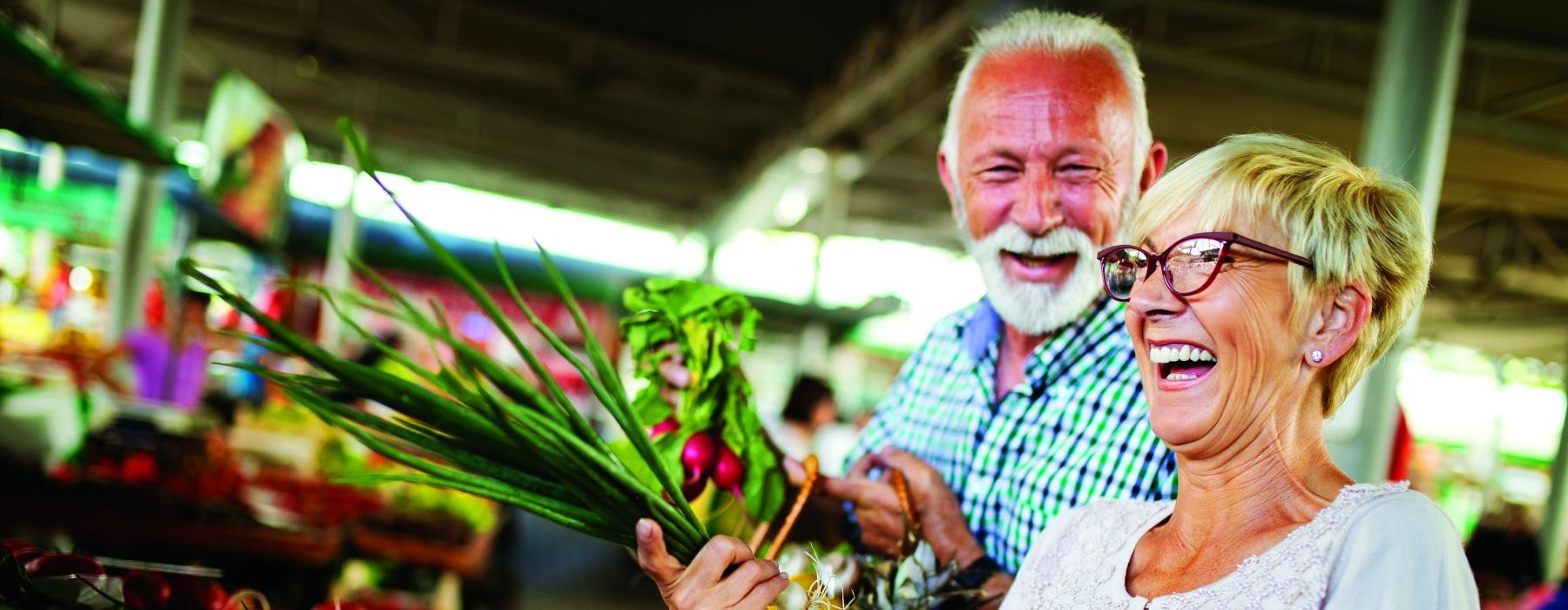 a man and woman holding a basket of vegetables