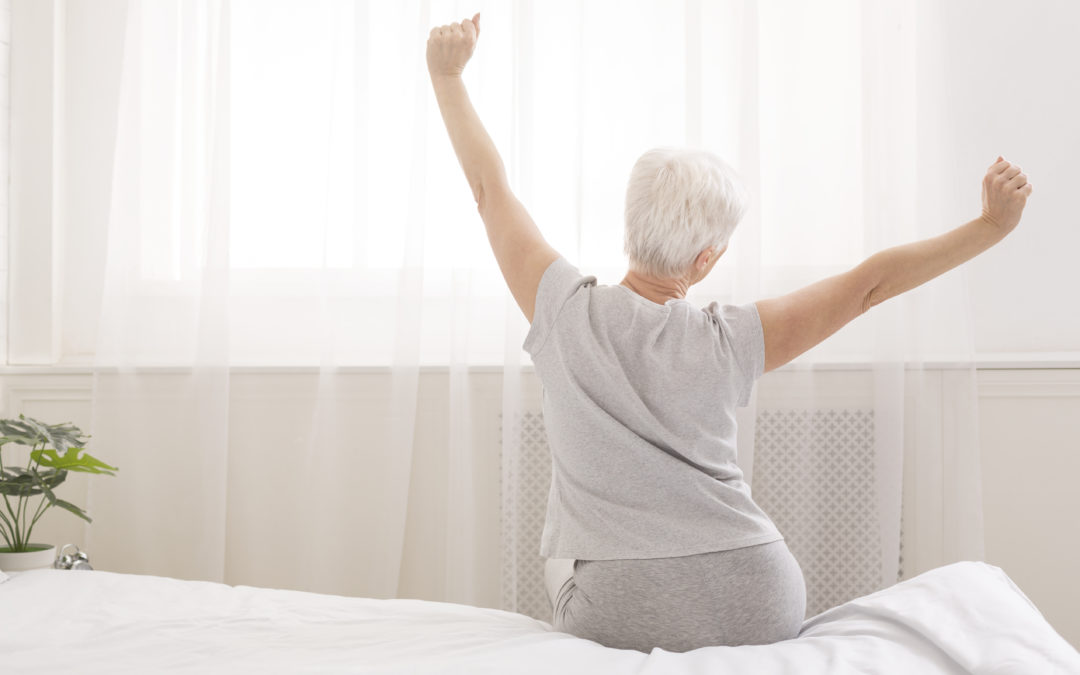 Senior woman sitting on her bed in morning